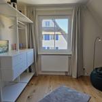 Schlafzimmer mit Fenster, Kleiderschrank und Sitzgelegenheit.