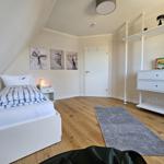 Schlafzimmer mit Bett, Schrank und Wandbildern.