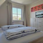 Schlafzimmer mit Doppelbett, Fenster und TV auf Schrank.
