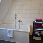 Bad mit Badewanne, Duschbrause und Handtuchständer.