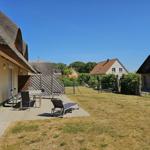 Terrasse mit Tisch, Stühlen und Liegen. Hinterhof mit Grasfläche und Nachbarhäusern.
