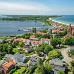 Aerial view of a coastal town with harbor, beach, and church.