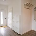 Eingangsbereich mit weißen Türen, Schuhschrank und runden Spiegel an der Wand.