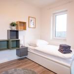 Ein Schlafzimmer mit Bett, Wandregalen und Fenster.