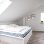 Schlafzimmer mit Dachschräge, Dachfenster, Bett und Schreibtisch.