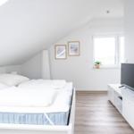 Schlafzimmer mit Dachbodenneigung, Bett, TV und Fenster.