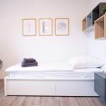 Schlafzimmer mit Bett, Fernseher und Wandregal.