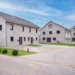 Drei moderne Wohnhäuser mit Steinfassade und Dachgauben.