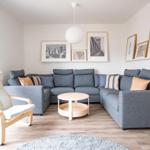 Ein Wohnzimmer mit grauem Sofa, Holzmöbeln und Wandbildern.