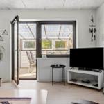 Wohnraum mit TV, Terrasse und Pflanze. Fenster und Tür offen.