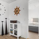 Raum mit Wanduhr, Steuerrad und Schrank. Durchgang zu Schlafzimmer mit Bett.