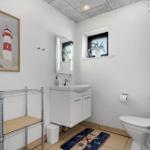 Badezimmer mit Waschbecken, Toilette und Fenster mit Pflanze.
