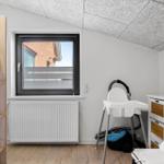 Zimmer mit Babyhochstuhl, Krippe und Fenster mit Blick.