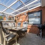 Gartenbereich mit Sitzgruppe, Grill und Glasdach.