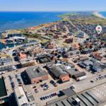 Aerial view of coastal town with harbor, beaches, and residential areas.