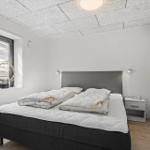 Schlafzimmer mit Doppelbett, Nachttisch und Fenster mit Jalousie.
