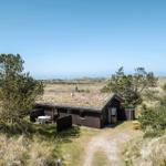 Holzhaus mit Terrasse und Grillplatz in einer grünen Umgebung mit Blick auf die Landschaft.
