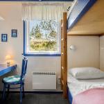 Zimmer mit Doppelstockbett, Schreibtisch und Fenster mit Blick auf Grünflächen.