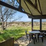 Terrasse mit Tisch und Stühlen, Blick auf Gras und Bäume.