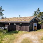Holzhütte mit Grasdach, Terrasse und Garten. Tisch und Stühle im Freien.