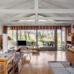 Wohn- und Essbereich mit Holzboden und großem Fensterblick auf Garten.