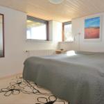 Schlafzimmer mit Bett, Wandspiegel und Fenstern