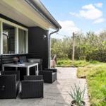 Terrasse mit Sitzgruppe, Grill und Blick auf Grünflächen.