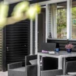 Außenbereich mit Tisch und Stühlen vor einem Haus mit schwarzem Holzschindelverkleidung.