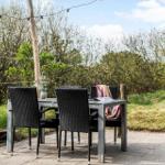 Außenbereich mit Tisch und Stühlen, umgeben von Grün und einem Steinweg.