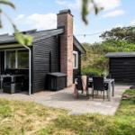 Schwarze Holzhütte mit Terrasse, Gartenmöbel und Grillplatz. Hinterhof mit Holzgarage.