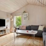 Wohnzimmer mit Holzwand, Sofa, Fernseher und Tisch.