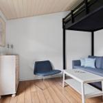 Wohnraum mit Sofa, Stuhl und Couchtisch. Obergeschoss mit Schlafplatz.