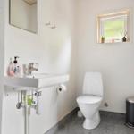 Badezimmer mit Waschbecken, Toilette und kleinem Fenster.