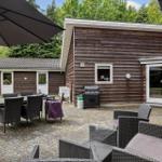 Terrasse mit Sitzgruppe, Tisch, Sonnenschirm und Grill. Holzhaus mit Fenster und Glastür.