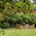 Garten mit drei Rattan-Sitzgelegenheiten und grüner Vegetation im Hintergrund.