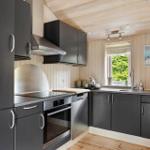 Küche mit dunklen Schränken, Edelstahlgeräten und Holzwandverkleidung.