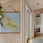 Wohnung mit Holzwand und Karte an der Wand. Tür führt in Schlafzimmer mit Bett und Schrank.