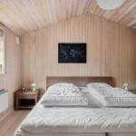 Schlafzimmer mit Holzwand, Bett, Nachttisch und Fenster