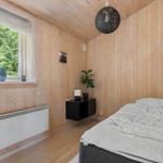 Schlafzimmer mit Holzwand, Bett, Fenster und Pflanze.