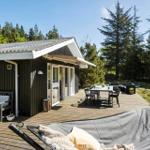 Holzterrasse mit Sitzgelegenheiten und Blick in den Wald.