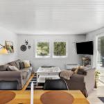 Wohnzimmer mit Sofa, Couch und TV. Durchgang zur Terrasse mit Blick auf den Pool.