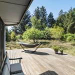 Terrasse mit Hängematte und Sitzbank, umgeben von Wald und Grün.