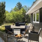 Terrasse mit Sitzgelegenheiten und Kaminfeuer neben einem Haus mit dunkler Fassade.