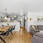 Wohn- und Essbereich mit Kücheninsel, Holzboden und weißer Wandverkleidung.