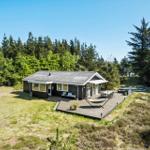 Ein Haus mit Terrasse, Hängematten und Grillplatz inmitten von Bäumen.