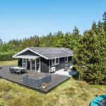 Moderne Ferienhaus mit großem Holzterrasse, Gartenmöbeln und Blick auf Wald.