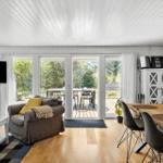 Wohn- und Essbereich mit Holzboden, TV, Sofa und Terrasse.