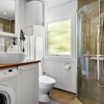 Badezimmer mit Dusche, Waschmaschine und Toilette. Fenster mit Blick auf Gras.