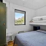 Zimmer mit Doppelbett, Schlafcouch und Fenster mit Blick auf Bäume.