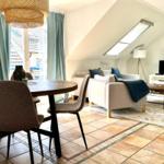 Wohn- und Essbereich mit Sofa, Tisch und TV unter Dachschrägen.
